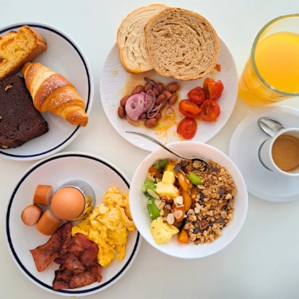 Colazione ricca con pane, uova, cereali e caffè.