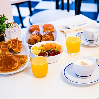 Colazione con waffle, croissant, frutta e succo d'arancia