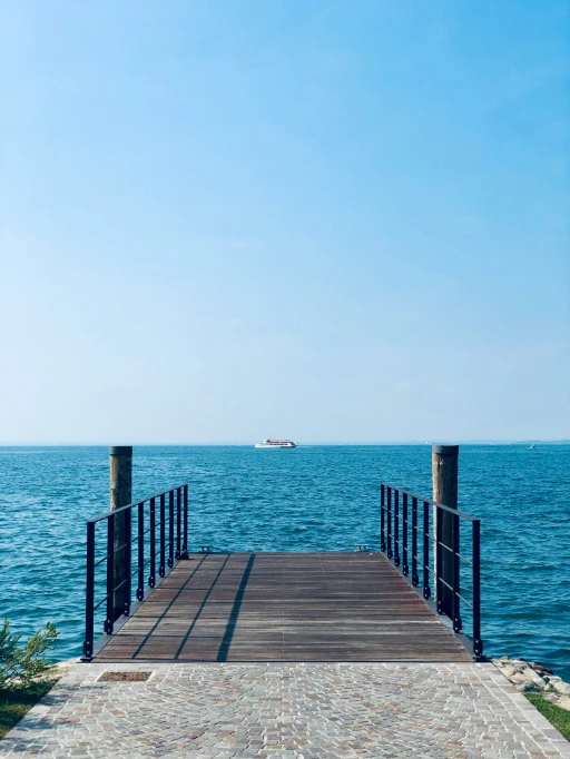 Pontile sul lago con barca in lontananza.