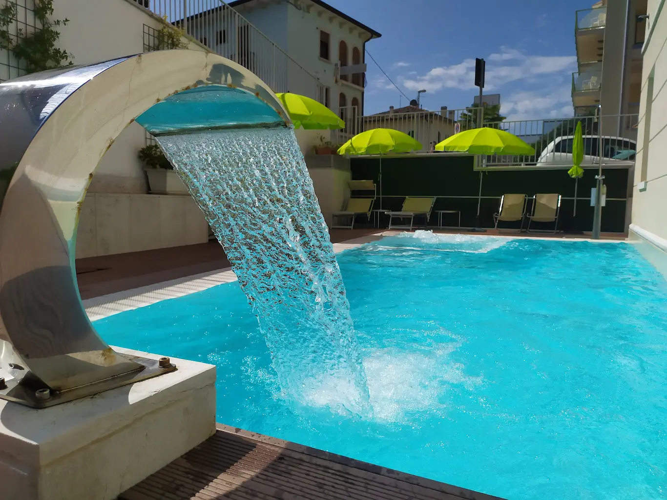 Piscina con cascata e ombrelloni verdi