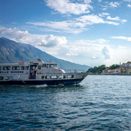 Traghetto sul Lago di Garda, montagne sullo sfondo.